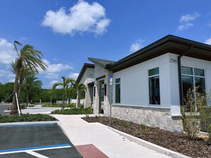 A modern building with a stone facade, large windows, and a clear blue sky. - Harry Potter~frozen Room 5BR w Game Room, Disney! (Kissimmee)