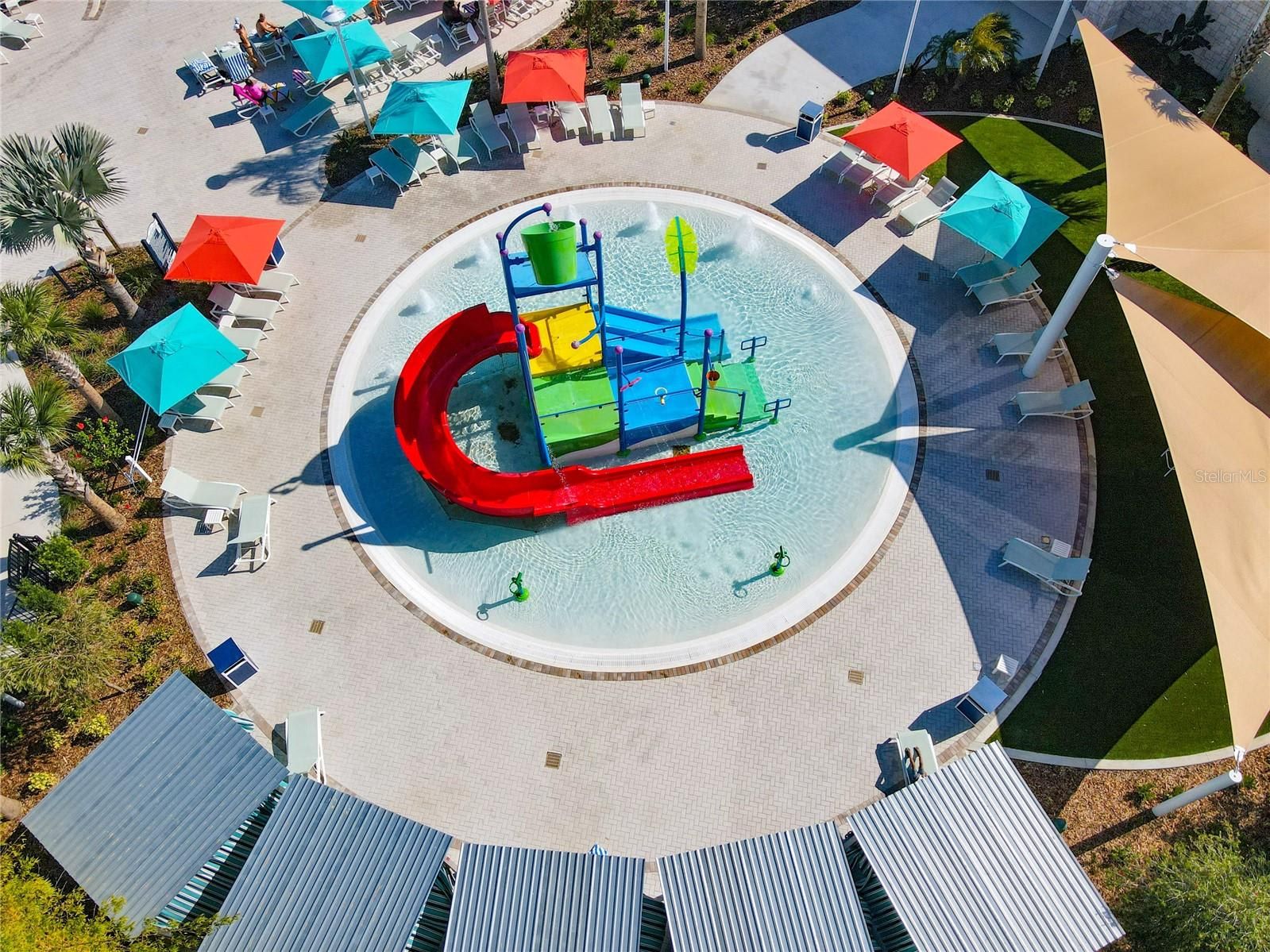 Zona de juegos acuáticos con toboganes y piscina, rodeada de sillones de descanso y sombrillas.