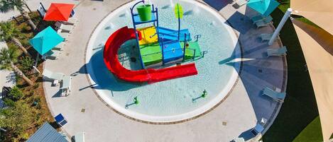 Zona de juegos acuáticos con toboganes y piscina, rodeada de sillones de descanso y sombrillas.