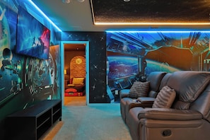 A room with a leather sofa, a television, and a wall with space-themed artwork. - Grand Marvel & Star Wars Villa Windsor Island (Davenport)