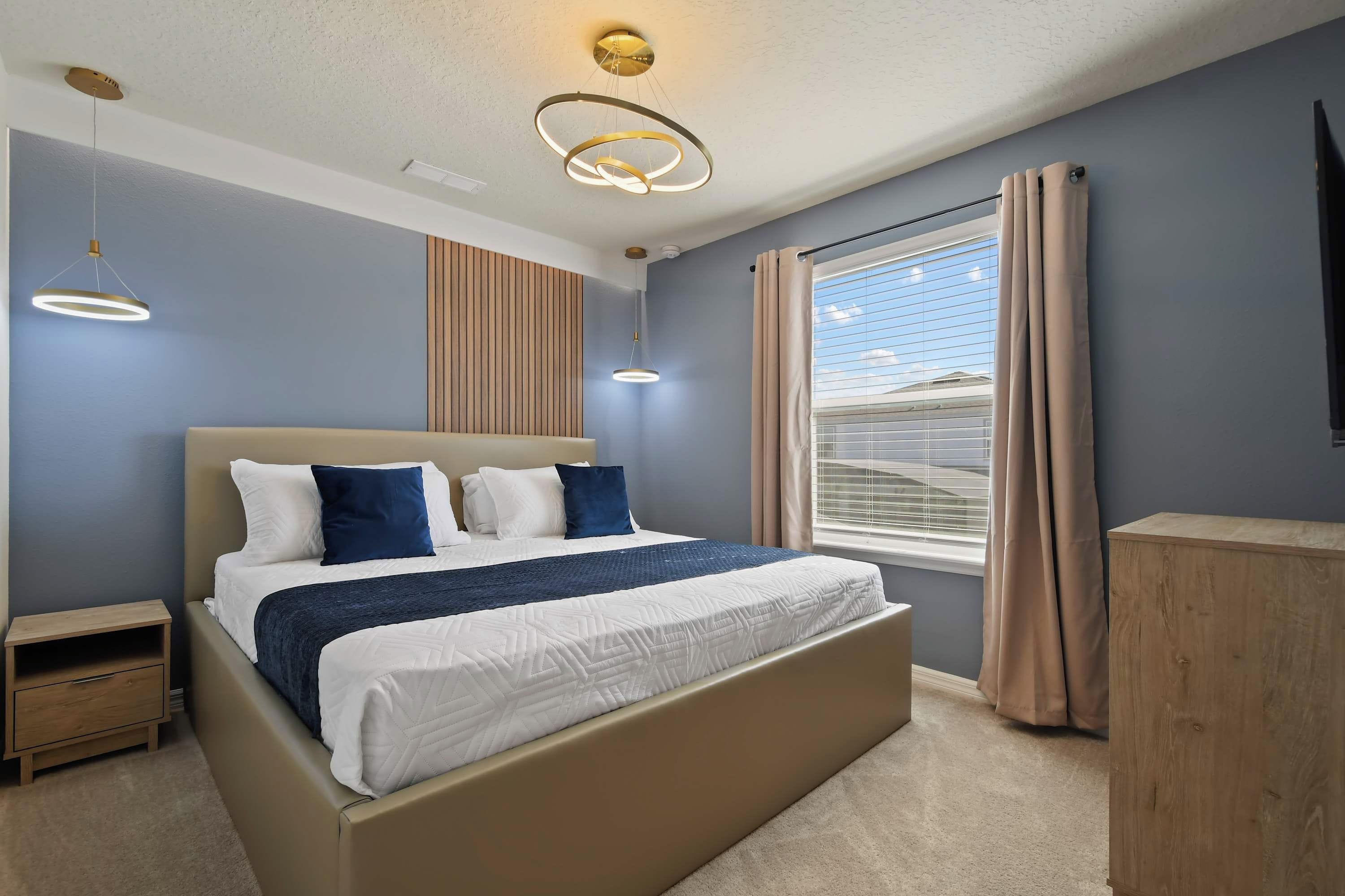 A bedroom with a bed, bedside tables, a wardrobe, a window with curtains, and a ceiling light fixture.