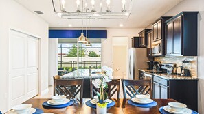 A modern kitchen with dark cabinets, stainless steel appliances, and a large island with seating. - Bright Minions & Hogwarts Escape Close to Disney (Davenport)