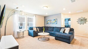 A living room with a sectional sofa, a coffee table, and a TV. - Bright Minions & Hogwarts Escape Close to Disney (Davenport)