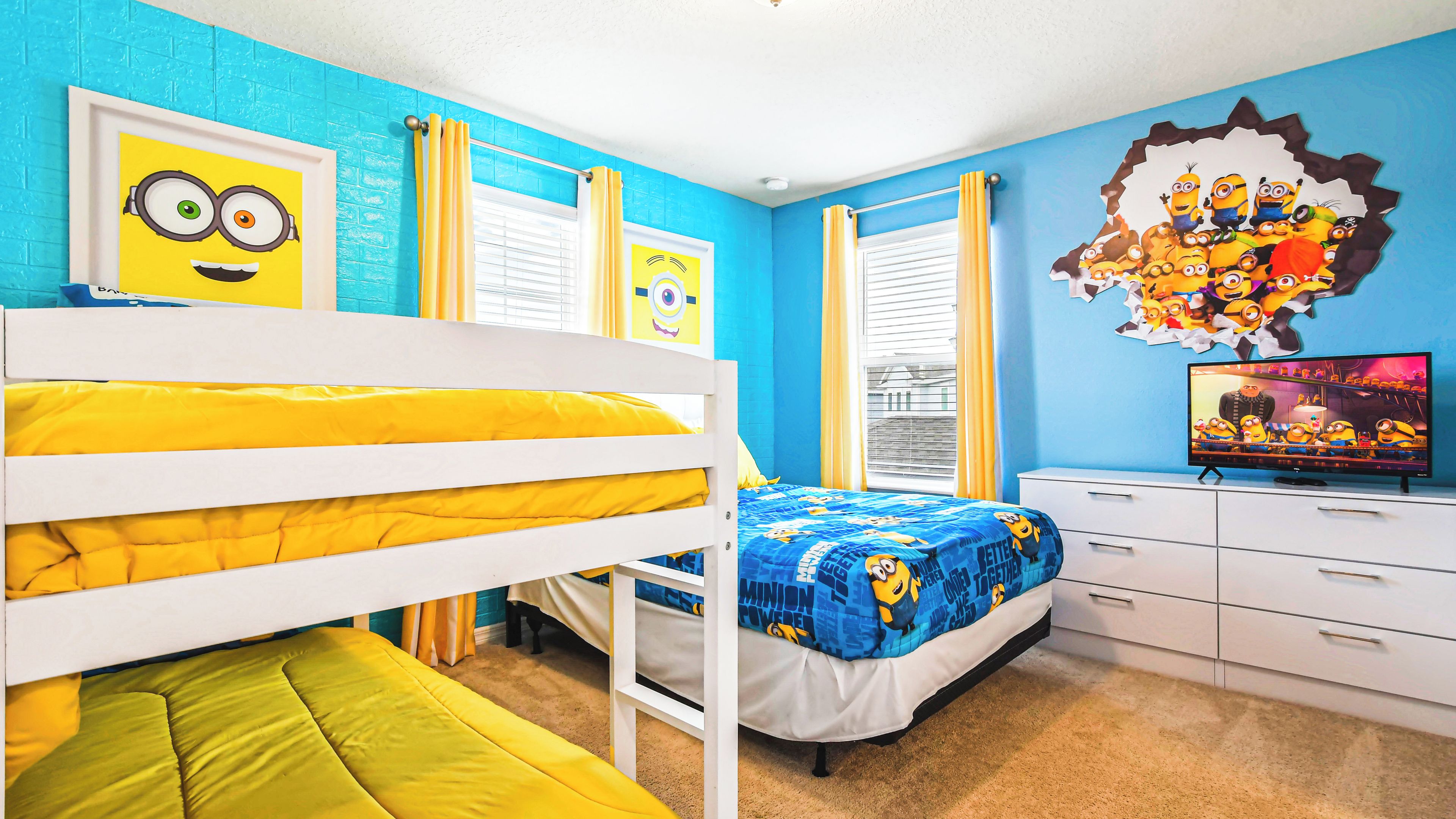 A bedroom with a bunk bed, a single bed, a dresser, and a wall with Minion-themed decorations.