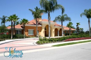 Ein Resort-Gebäude mit rotem Ziegeldach, Bogenportal und Palmen.