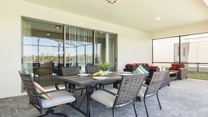 An outdoor patio with a dining table, chairs, and a seating area with cushions. - Star Wars/harrypotter Bunks, Pool, Lake View, 8br! (Kissimmee)