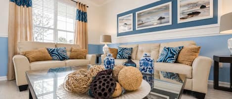 A living room with two sofas, a coffee table with decorative items, and a wall with framed artwork.