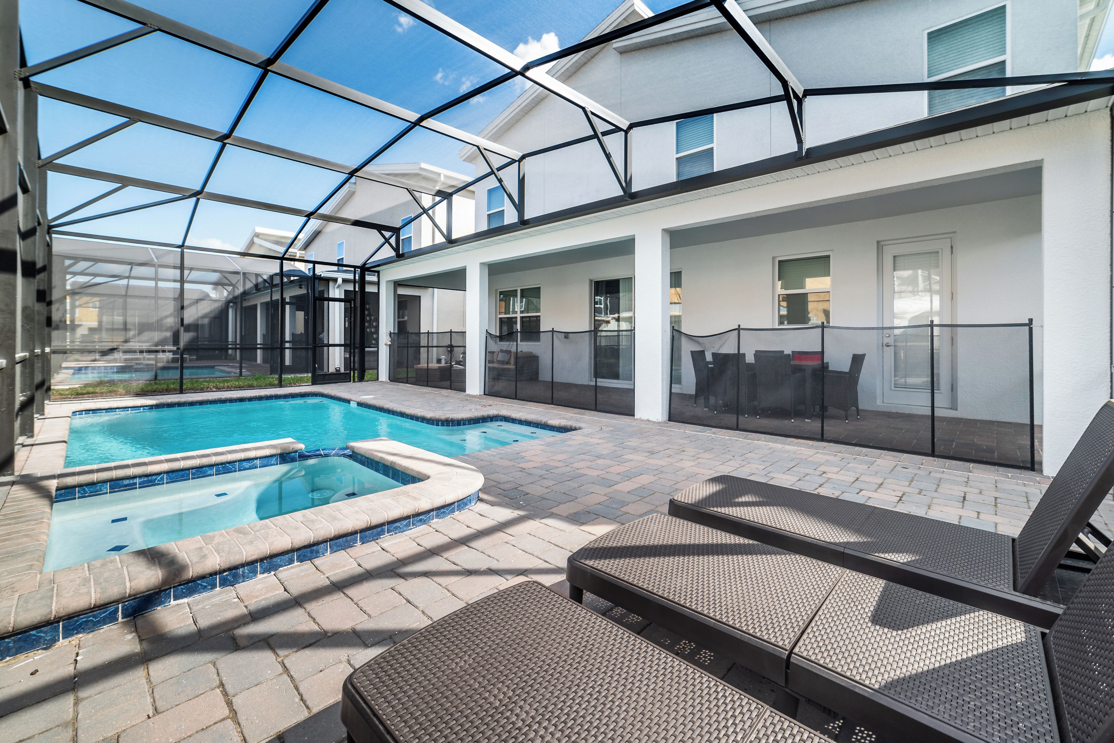 A covered outdoor swimming pool with lounge chairs and a patio area.