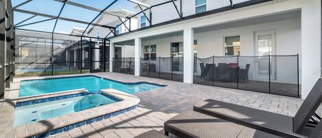 Une piscine extérieure couverte, dotée de chaises longues et d’un espace patio.