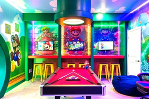 A pool table with a Mario-themed backdrop, a neon-lit ceiling, and Mario and Luigi posters on the walls. - Loaded Mario Gameroom, Theatre, Themed Rooms 10br! (Kissimmee)