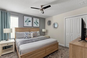 A bedroom with a bed, two bedside tables, a ceiling fan, artwork on the wall, and a television on a stand. - Loaded Mario Gameroom, Theatre, Themed Rooms 10br! (Kissimmee)