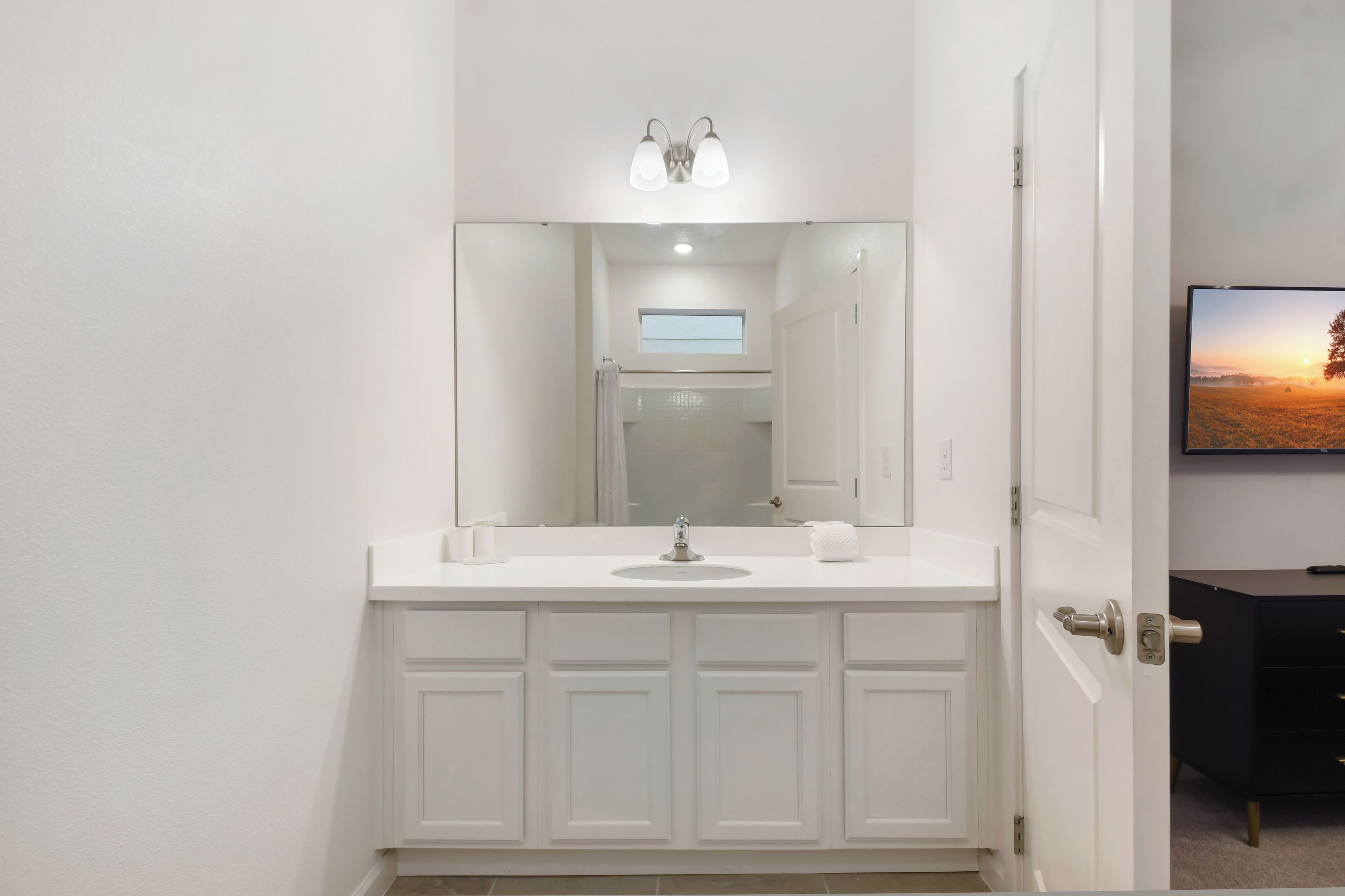 A modern bathroom with a white vanity, a mirror, and a recessed ceiling light.