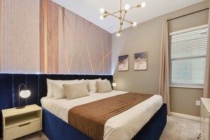 Een moderne slaapkamer met een groot bed, een nachtkastje, een wandlamp en een raam met gordijnen.
