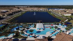 A large swimming pool with a water slide, surrounded by lounge chairs and umbrellas. - Fun Family Home Mario Game Room & Star Wars (Kissimmee)