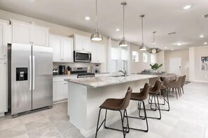 A modern kitchen with a central island, stainless steel appliances, and pendant lighting. - 5BR Near Parks w Themed Rooms, Pool @ Solterra (Davenport)
