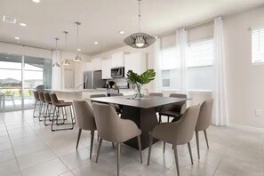 A modern kitchen with a central island, bar stools, and pendant lighting. - 5BR Near Parks w Themed Rooms, Pool @ Solterra (Davenport)