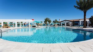 A large outdoor swimming pool with lounge chairs and umbrellas, surrounded by palm trees and a white gazebo. - Private Pool Home W/star Wars Game Loft (Kissimmee)