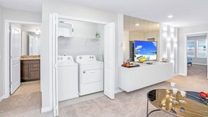 A modern kitchen with built-in appliances, a dining area with a glass table, and a view of the beach through a large window. - Family Home w Large Dining~frozen Room~resort Pool (Davenport)