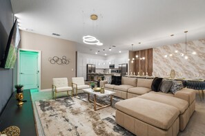 Una sala moderna con un sofá modular, una mesa de centro y un comedor con salpicadero de mármol.