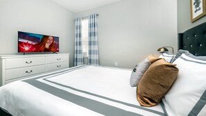 A bedroom with a bed, a television on a dresser, a window with curtains, and a bedside lamp. - Close2parks, 7br, Themed Room @ Windsor Hill! (Kissimmee)
