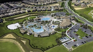 An aerial view of a residential area with multiple houses, a swimming pool complex, and a parking lot. - Spacious Champions Gate Home for Family Getaways (Davenport)