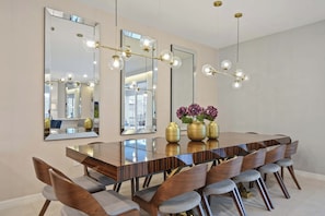 A dining area with a long wooden table, multiple chairs, and large mirrors on the walls. - 10br Windsor Epic Themed Villa Private Pool (Davenport)