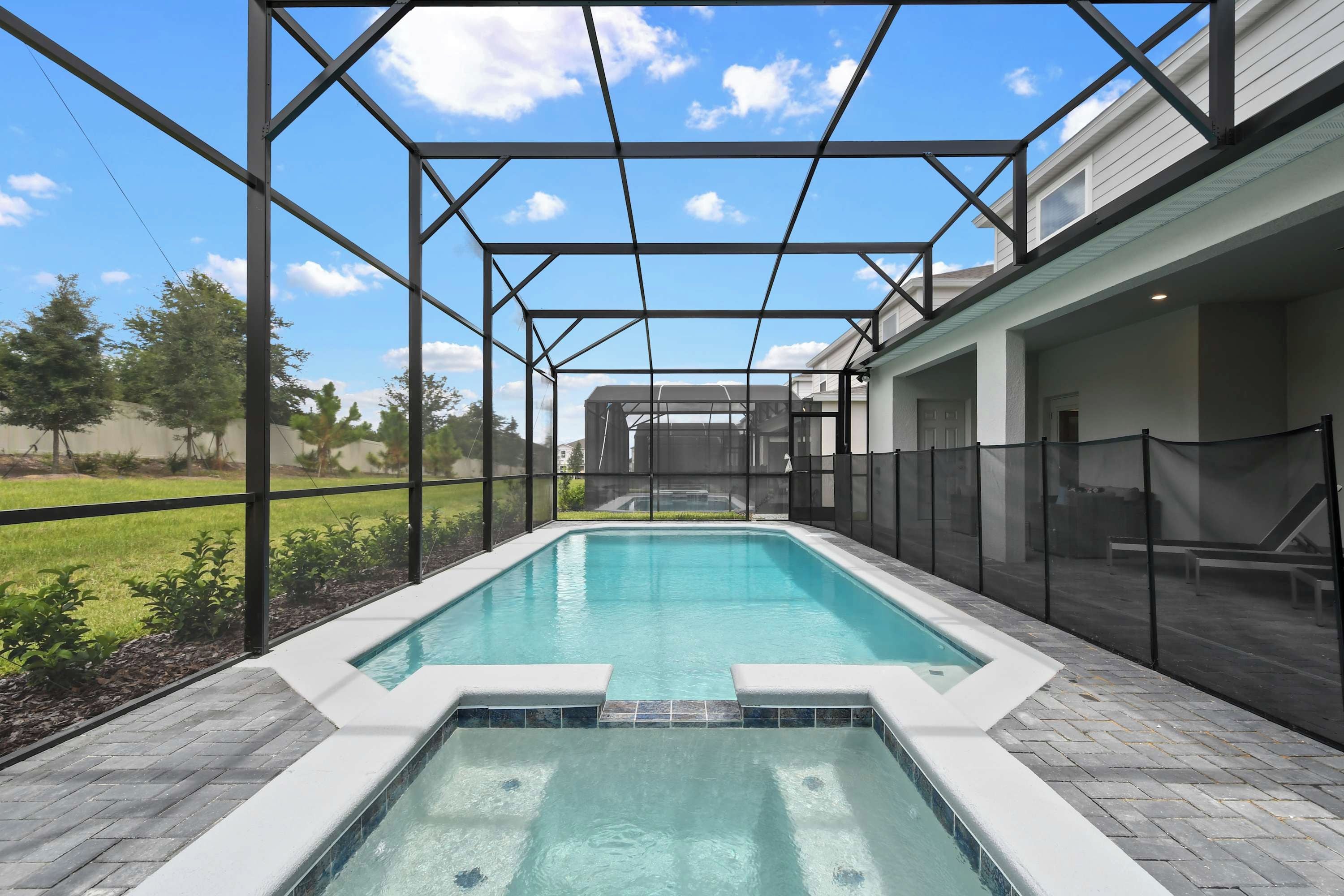 A rectangular outdoor pool with a clear blue water surface, surrounded by a black metal frame and a glass enclosure.