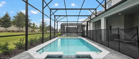 A rectangular outdoor pool with a clear blue water surface, surrounded by a black metal frame and a glass enclosure.