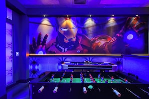 A room with a foosball table and a large screen displaying an Iron Man image. - 10br Windsor Epic Themed Villa Private Pool (Davenport)