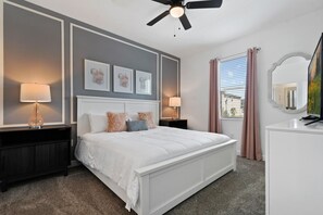 Ein Hotelzimmer mit einem großen Bett, zwei Nachttischen, einem Deckenventilator und einem Fenster mit Vorhängen.