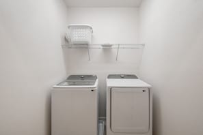 A laundry area with two stacked washing machines and a drying rack above. - Nice 15br Home Near Disney Groups Welcome (Kissimmee)