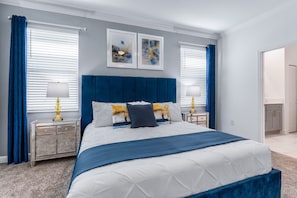 Ein Schlafzimmer mit einem großen Bett, zwei Nachttischen, einem Kopfteil und Kunstwerken an der Wand.