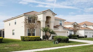 A multi-story residential building with a flat roof, a central entrance with columns, and a well-maintained lawn. - Pool, Hot Tub & Nautical Magic Near Disney (Kissimmee)