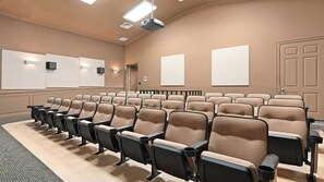 A conference room with rows of beige chairs, a carpeted floor, and a projector screen on the wall. - Pool, Hot Tub & Nautical Magic Near Disney (Kissimmee)