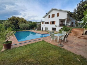 A residential property with a swimming pool, a patio with outdoor furniture, and a white house with multiple windows. - CASA EN EL MONTSENY CON JARDIN Y PISCINA PARTICULAR (CT)