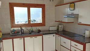Une cuisine avec une fenêtre, un ventilateur de plafond et une horloge au mur.