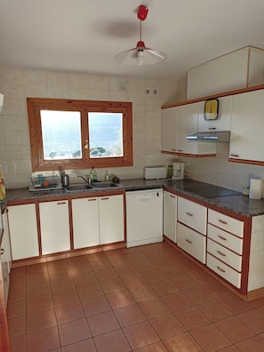 A kitchen with a window, a ceiling fan, and a clock on the wall. - CASA EN EL MONTSENY CON JARDIN Y PISCINA PARTICULAR (CT)