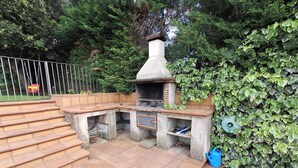 Un espace cuisine extérieur doté d’un four en briques, d’un escalier menant à cet espace et d’un tuyau d’arrosage.