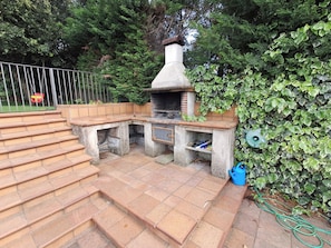 An outdoor kitchen area with a brick oven, steps leading up to it, and a garden hose. - CASA EN EL MONTSENY CON JARDIN Y PISCINA PARTICULAR (CT)
