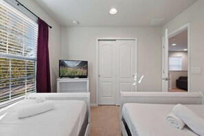 A hotel room with two beds, a television on a stand, a door, and a window with blinds. - Cozy 5BR Townhome w/ Mickey Themed & Pool (Kissimmee)