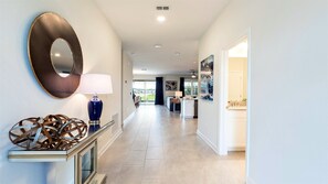 A hallway with a mirror, a blue lamp, and abstract art on the wall. - Lakeview/star Wars & Minions Rooms + Resort Access (Kissimmee)