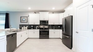 A modern kitchen with white cabinets, a black refrigerator, a microwave, and a stove. - Lakeview/star Wars & Minions Rooms + Resort Access (Kissimmee)