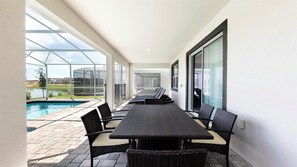 A covered patio with a pool, outdoor furniture, and a view of the surrounding landscape. - Lakeview/star Wars & Minions Rooms + Resort Access (Kissimmee)