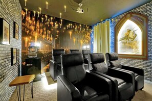 A room with black leather chairs, a projector screen, and a mural with hanging lights. - Star Wars & Jurassic Park Fun Near Disney (Kissimmee)