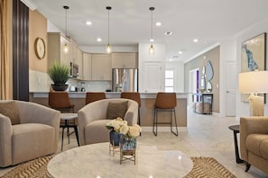 A modern living room with a marble coffee table, beige sofas, and a decorative vase with flowers. - Lakeview Villa Epic Game Room & Pool (Kissimmee)