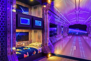 Une pièce futuriste avec un lit superposé, des panneaux de contrôle et une vue sur l’espace.
