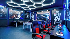 Una sala de juegos con una mesa de fútbol de mesa, varias sillas de juego y decoración temática de Star Wars.