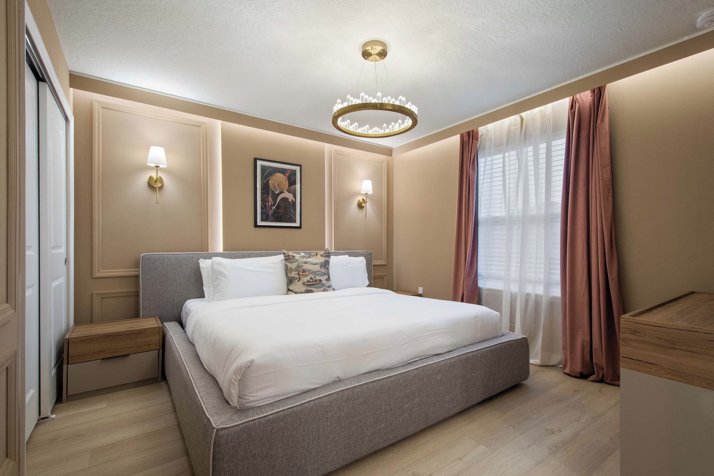 A bedroom with a large bed, bedside tables, wall-mounted lamps, a ceiling light, and a window with curtains.