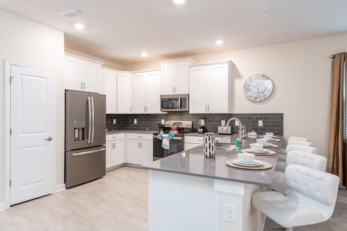 A modern kitchen with white cabinets, stainless steel appliances, and a central island with seating.