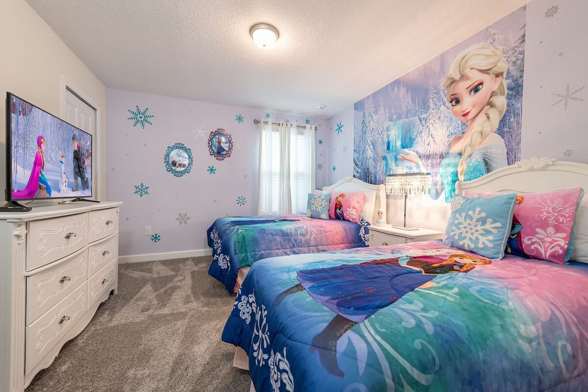 A bedroom with two beds, a dresser, a TV, and a wall mural.